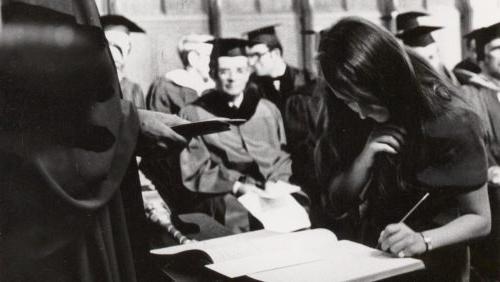 Female student matriculates at Trinity College, signing the matriculation book in Trinity College Chapel