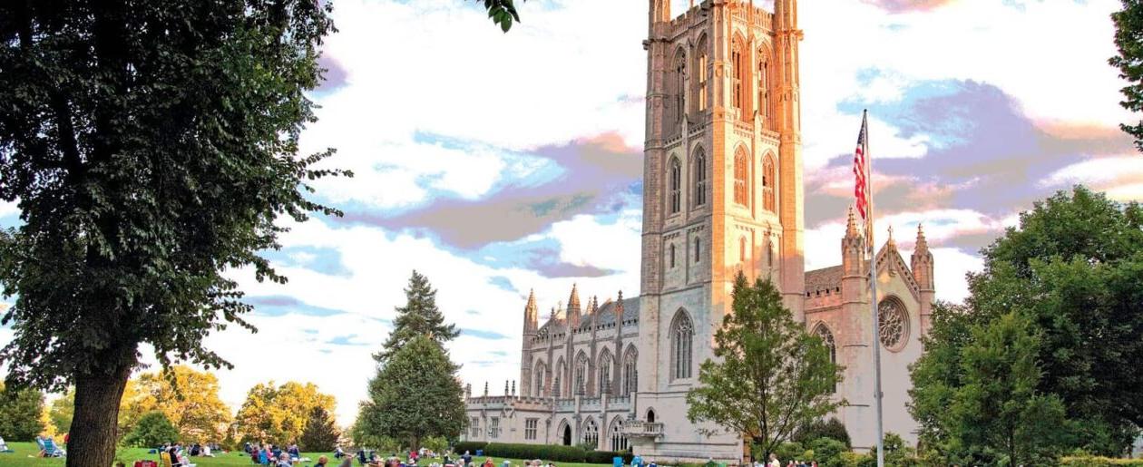 The Trinity College Chapel with students sitting on the grass