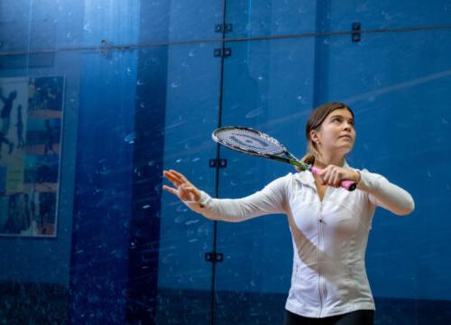 Trinity college squash player serving the ball with racket